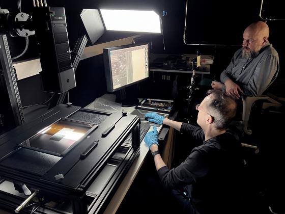 2 menn i eit black box studi jobbar med avansert fotoutstyr og data.